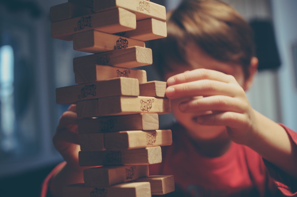 Unfocused image of young boy playing Jenga by stacking blocks