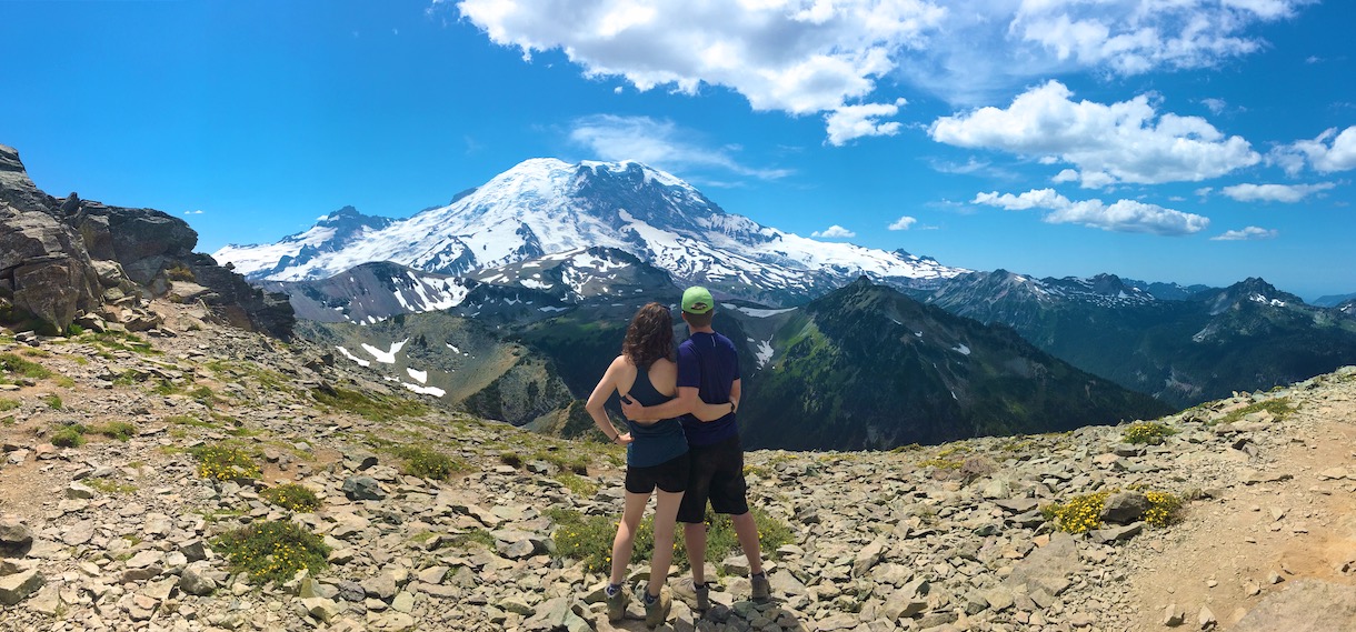 man and woman (Amber) staring at Mount Rainier on a cliff edge